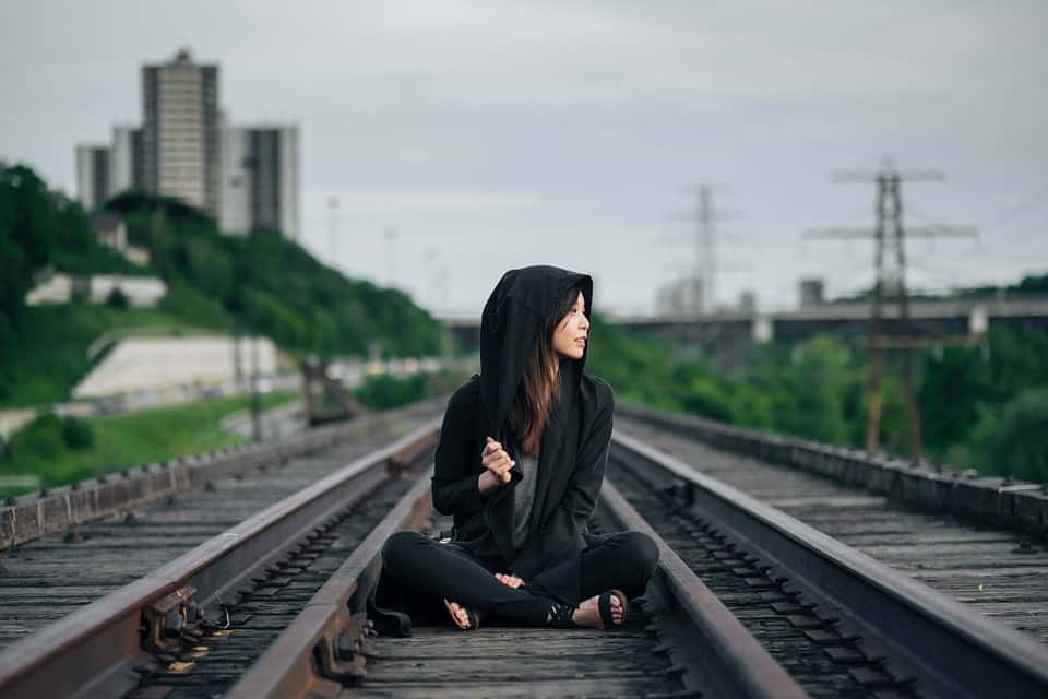 A Korean woman sits on a train line waiting to go somewhere, maybe?